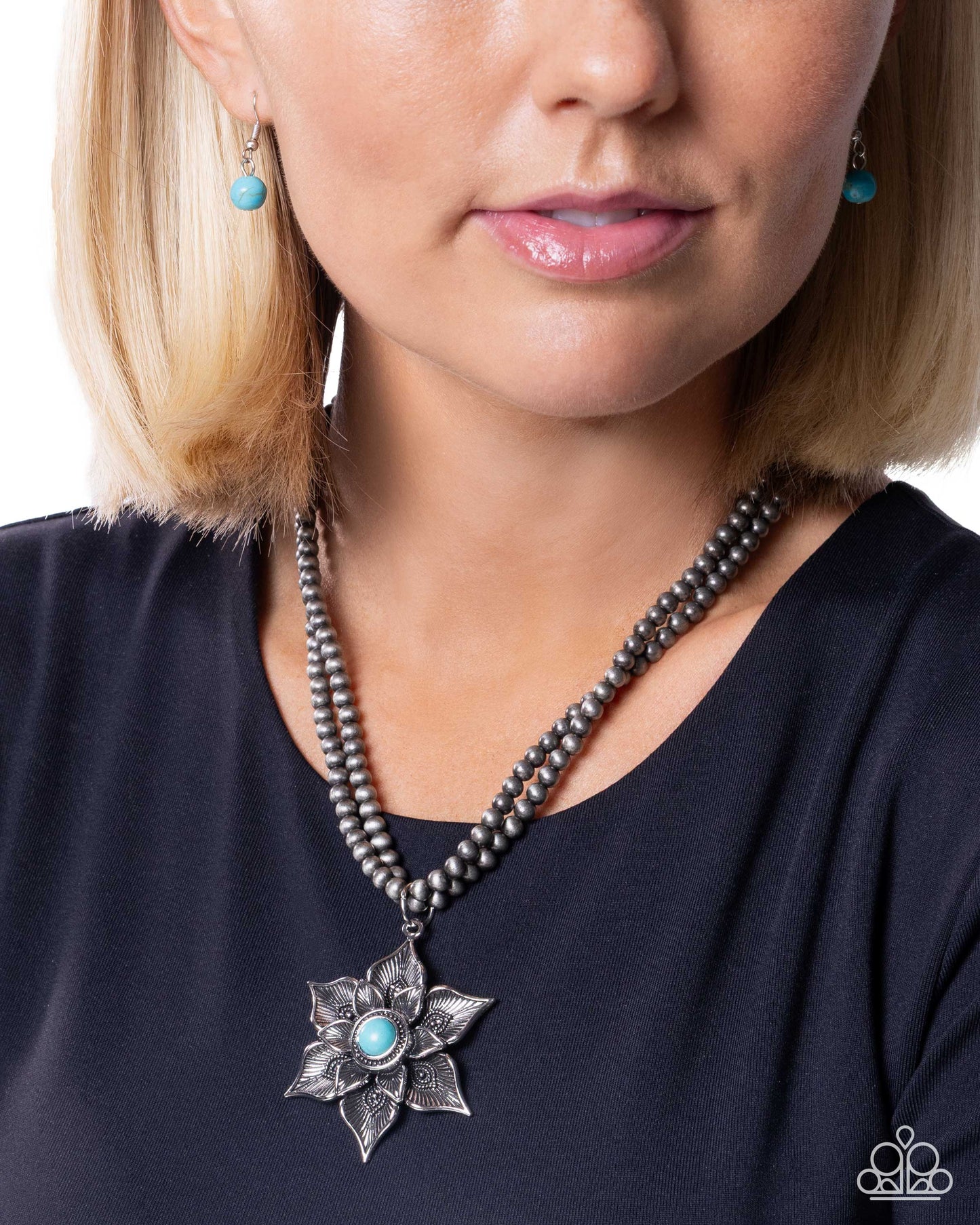 Woman wearing a beaded necklace with a silver flower pendant and turquoise stones.