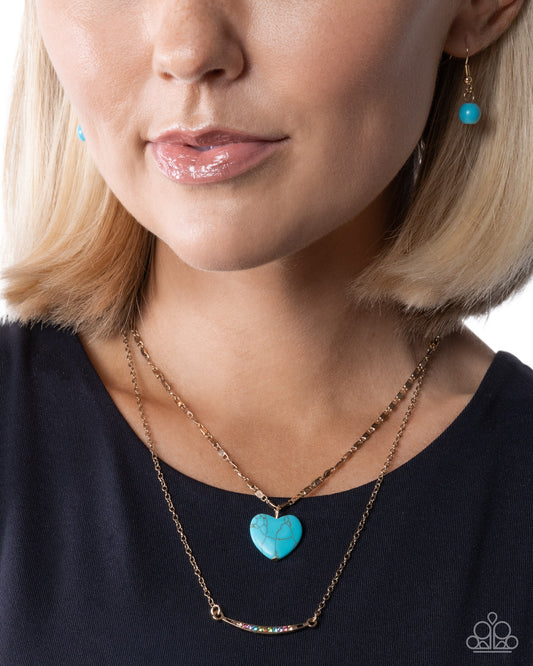 Close-up of a woman wearing a turquoise heart pendant necklace and matching earrings.