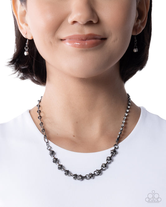 Person wearing a black beaded necklace on a white background