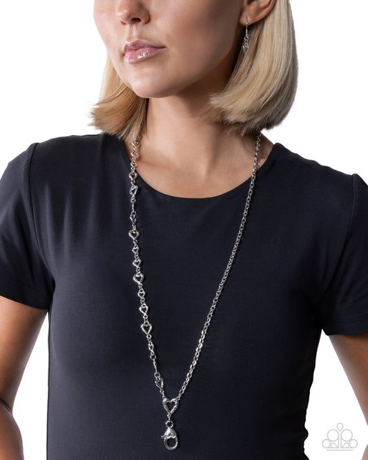Woman wearing a long silver chain necklace against a white background