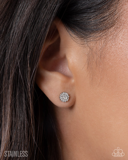 Close-up of an ear wearing a silver earring with 'Stainless' text below.