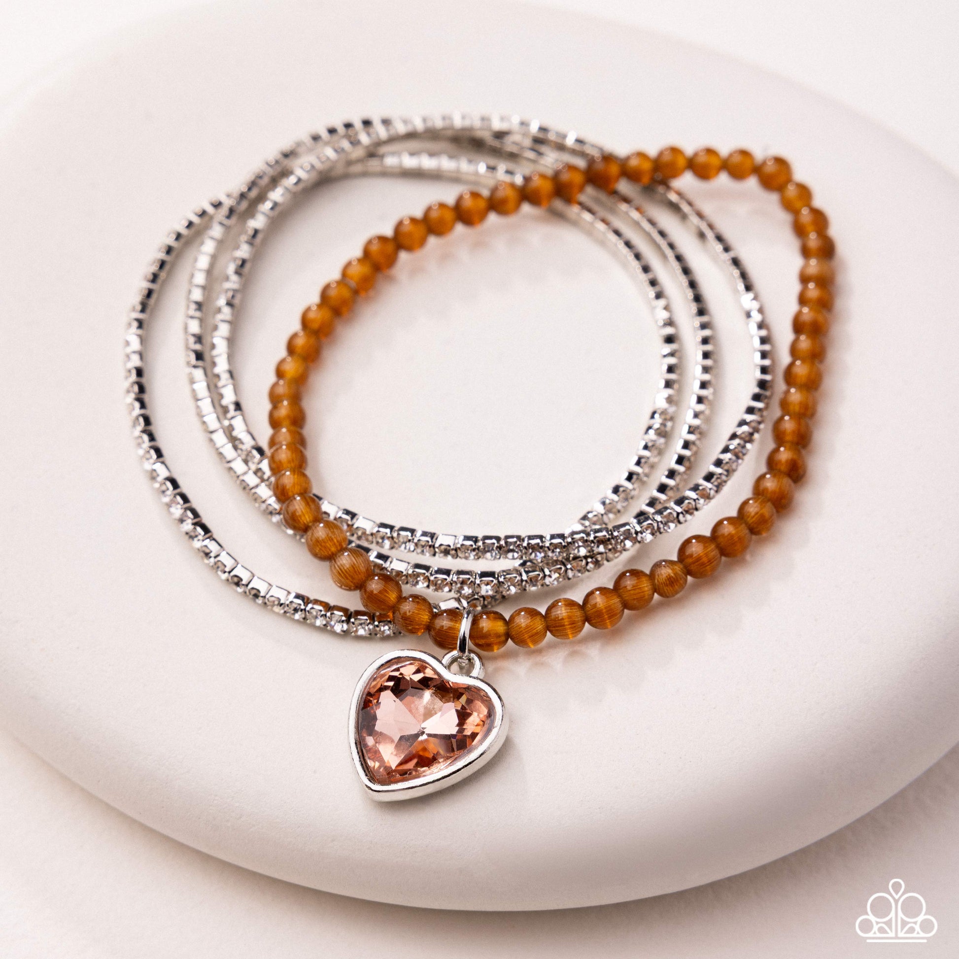 Stack of beaded bracelets with a heart-shaped charm on a white surface