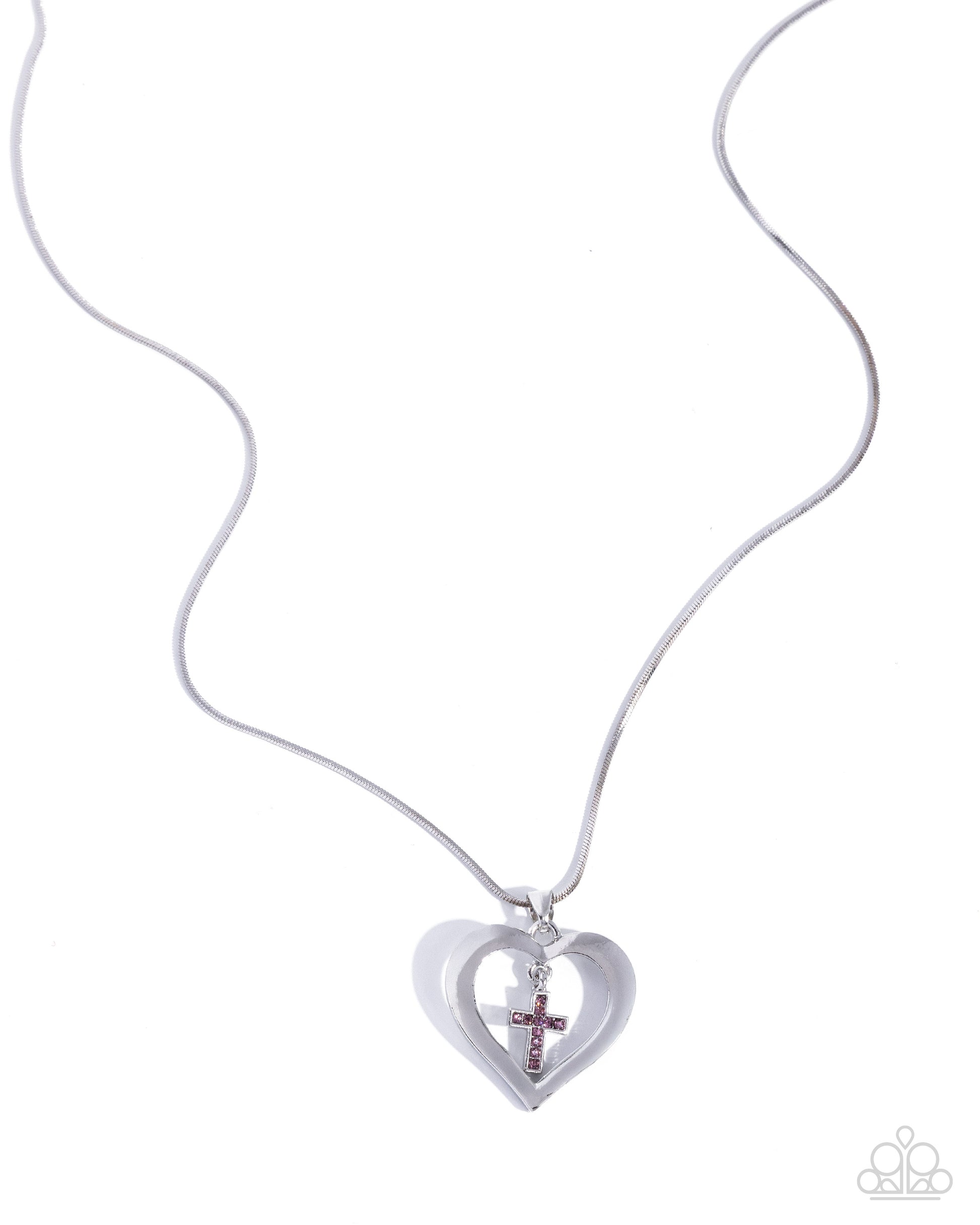 Heart-shaped pendant with cross and red gemstone on white background