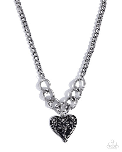 Silver chain necklace with a heart-shaped pendant on a white background