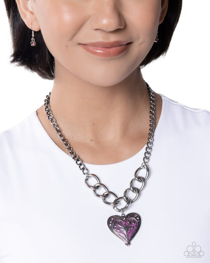 Person wearing a silver chain necklace with a purple heart pendant on a white background