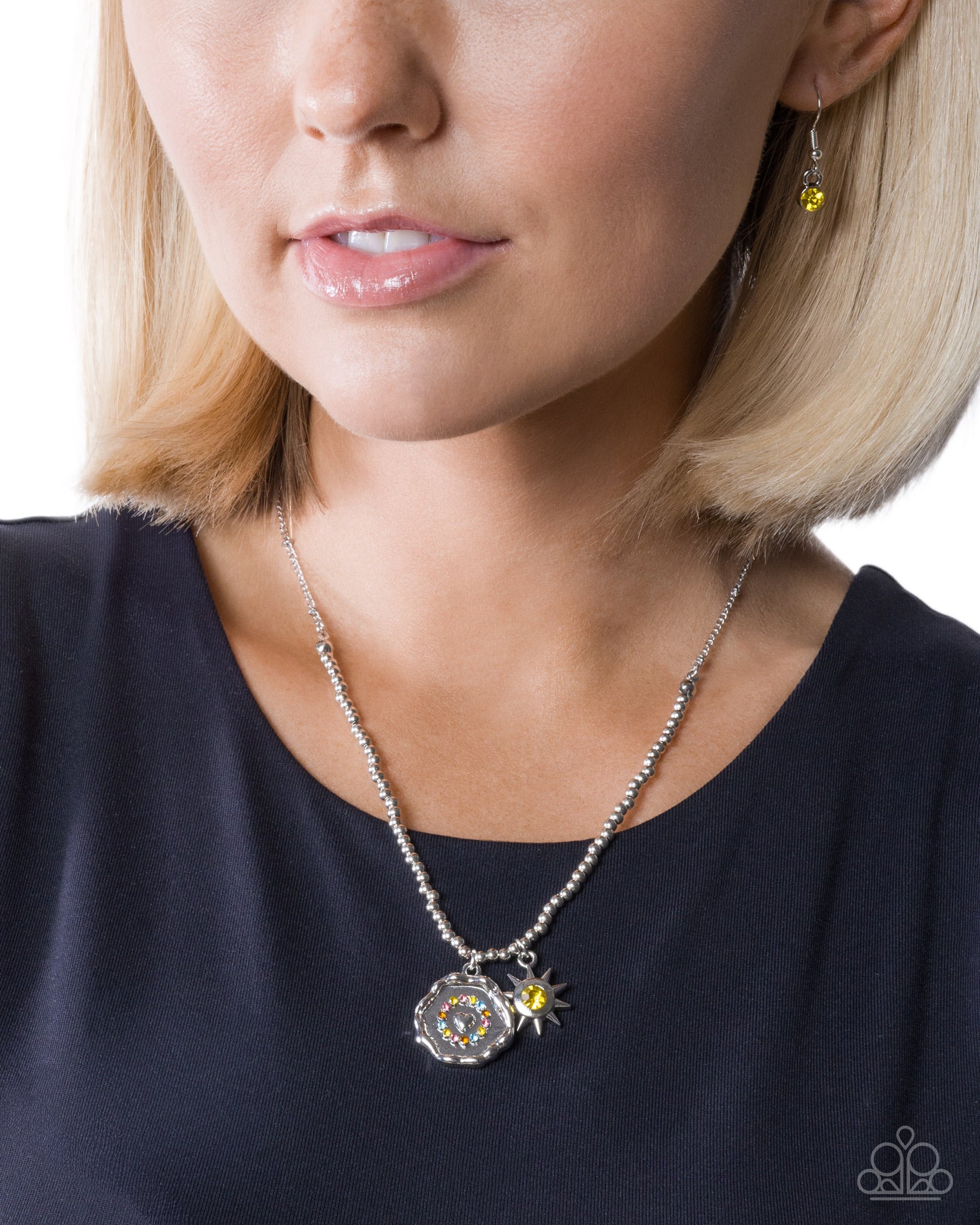 Close-up of a woman wearing a silver necklace with a yellow pendant on a white background