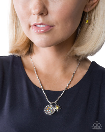 Close-up of a woman wearing a silver necklace with a yellow pendant on a white background