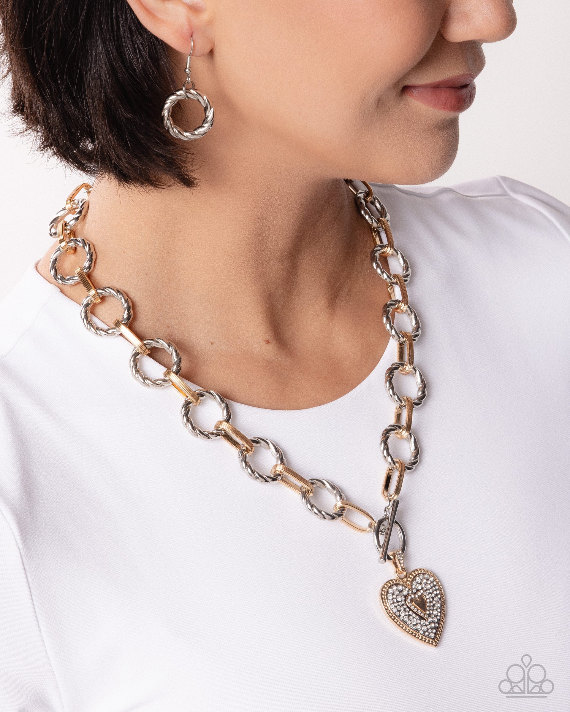 Person wearing a gold chain necklace with a heart-shaped pendant on a white background