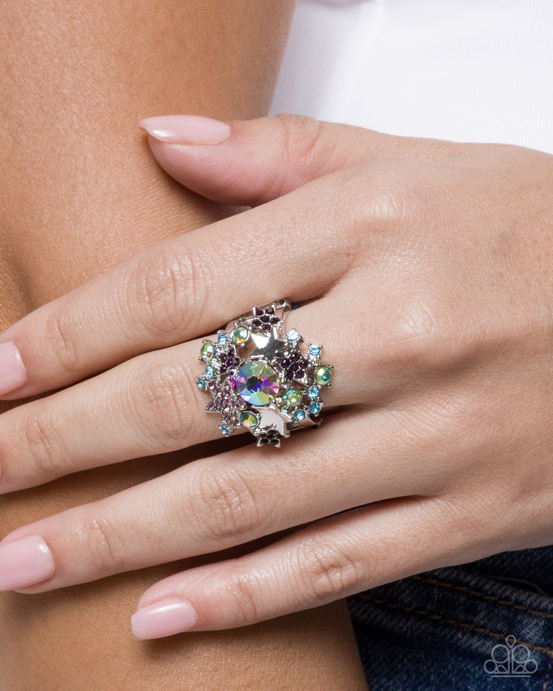 Close-up of a hand wearing a decorative ring with multicolored gemstones.
