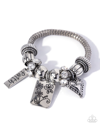 Silver bracelet with various charms on a white background