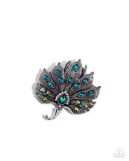 Peacock feather brooch with blue gemstones on a white background