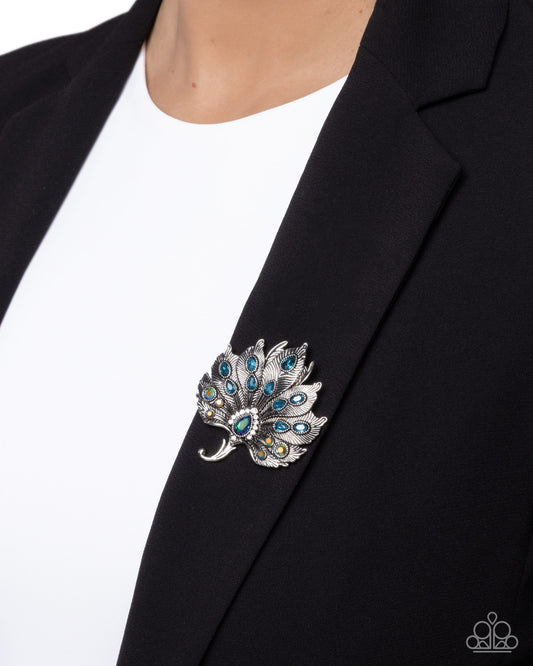 Silver brooch with blue gemstones on a black blazer
