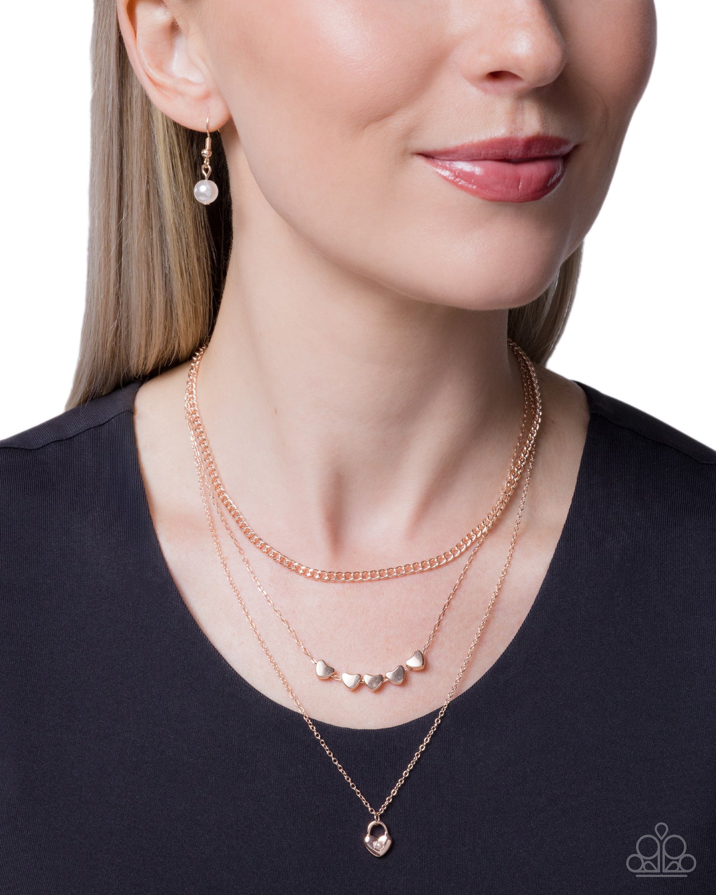 Woman wearing a rose gold necklace with small round pendants on a plain background