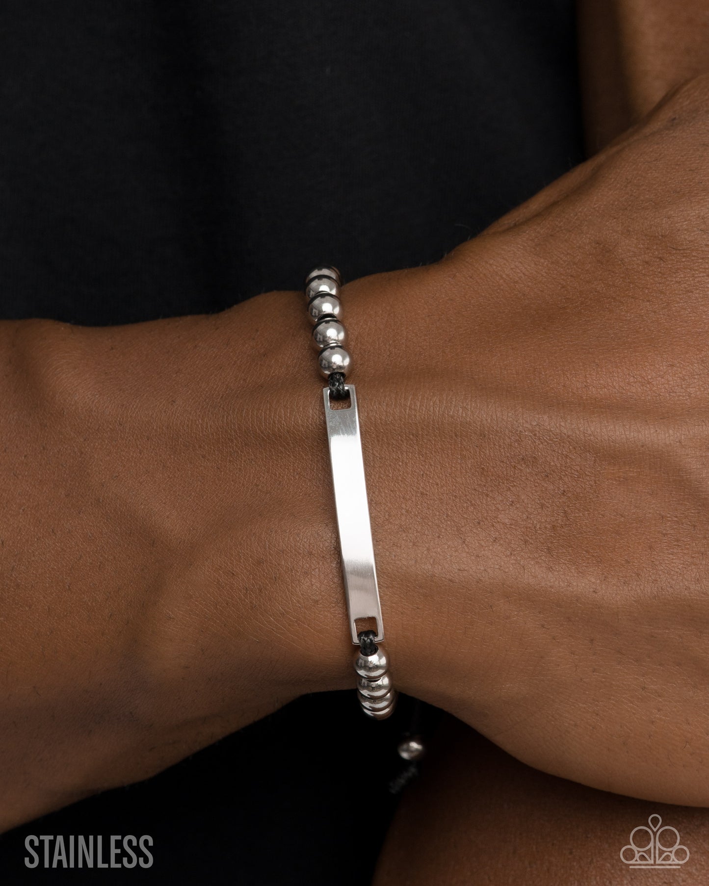 Silver bracelet on a wrist with a plain background