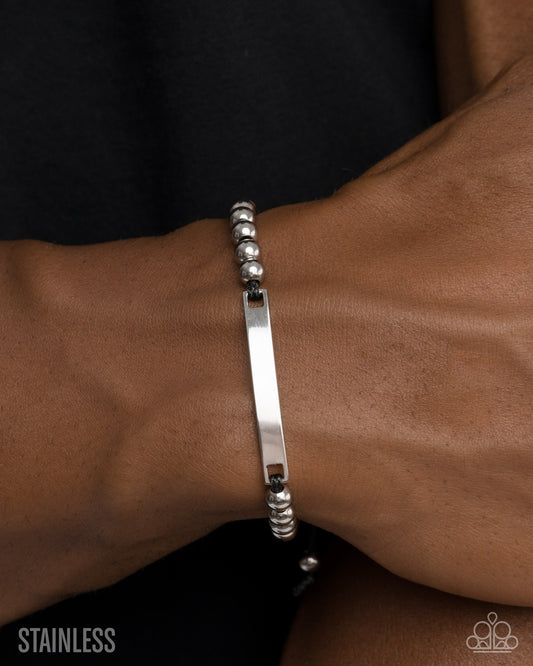 Silver bracelet on a wrist with a plain background