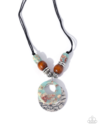 A bohemian-style necklace featuring a large circular stone pendant with turquoise, brown, and silver marbled patterns, suspended on a black cord with matching accent beads and silver spacer rings.