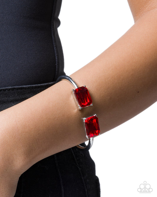 Bracelet with red gemstones on a wrist against a black background
