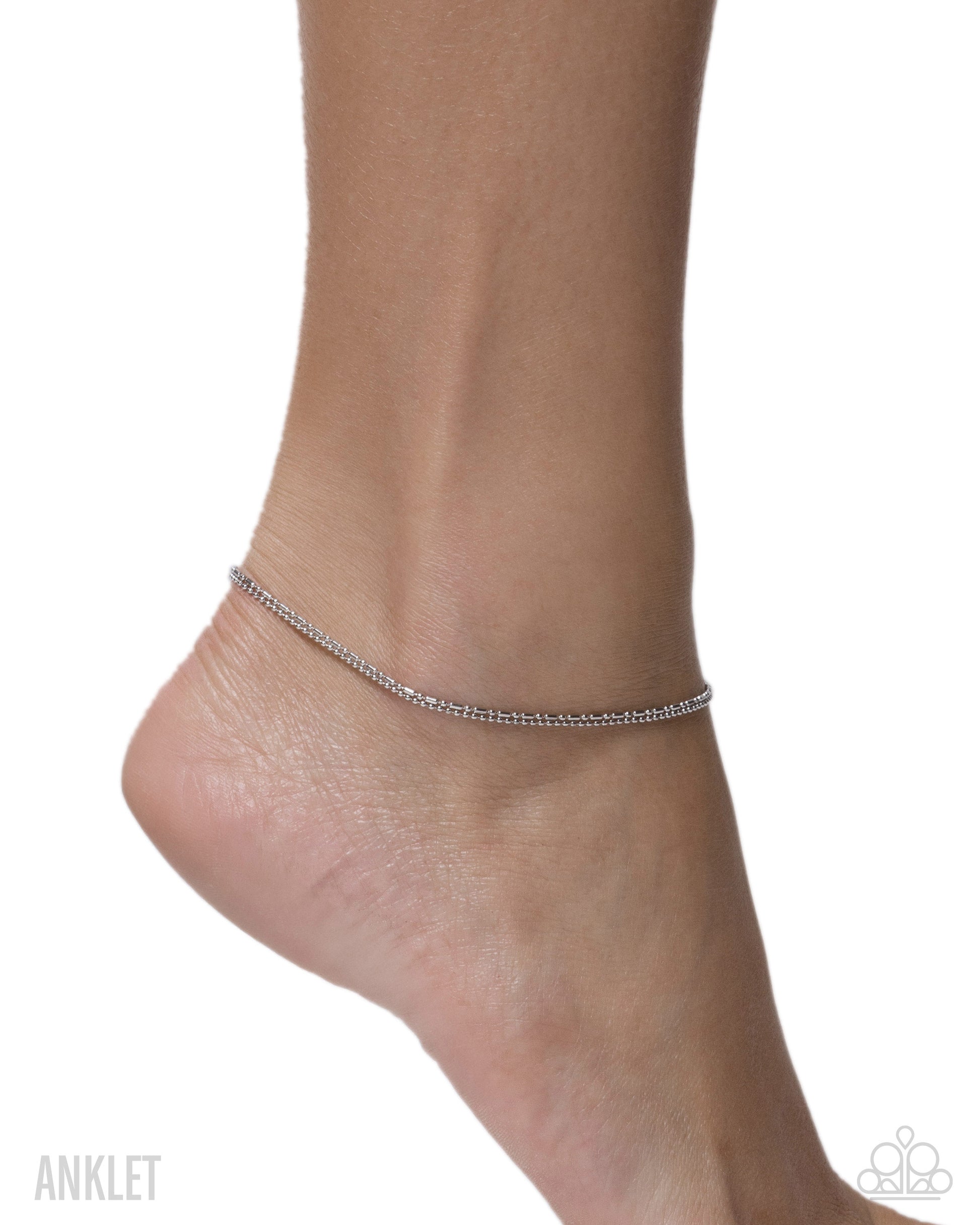 Silver anklet on a foot against a white background