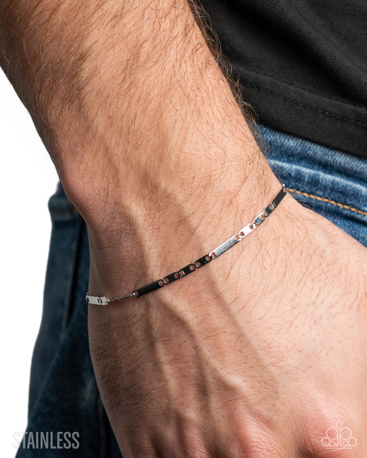 Close-up of a wrist wearing a silver bracelet with a blurred background