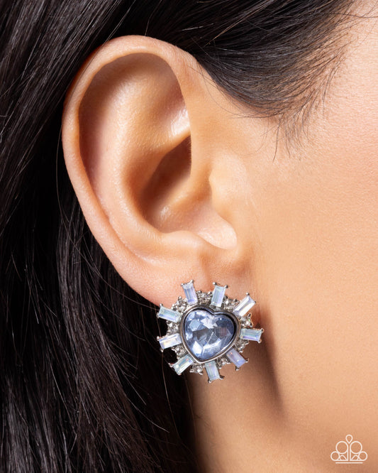 Close-up of an ear wearing a silver and blue earring with a starburst design.
