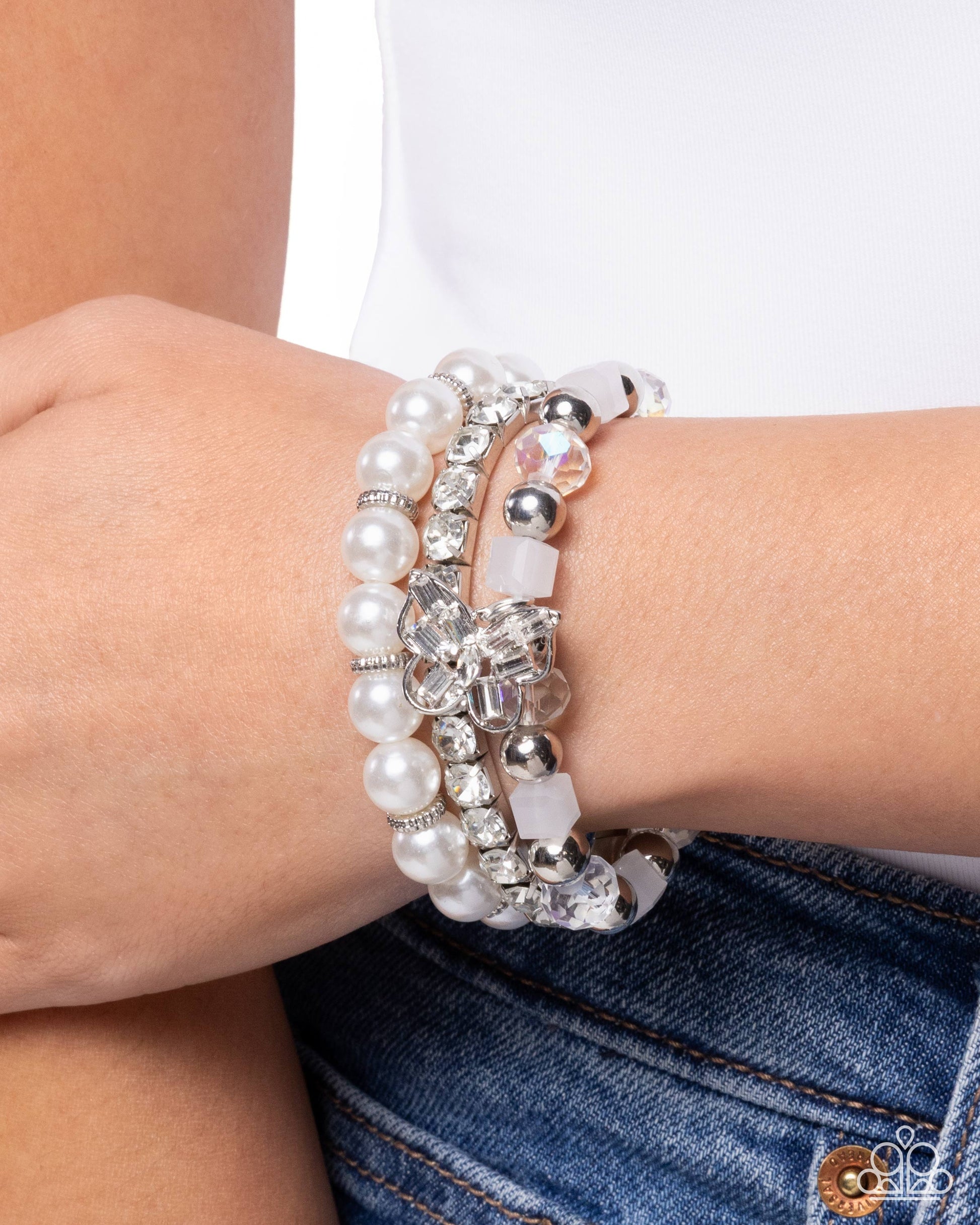 Stack of pearl and crystal bracelets on a wrist with a blurred background