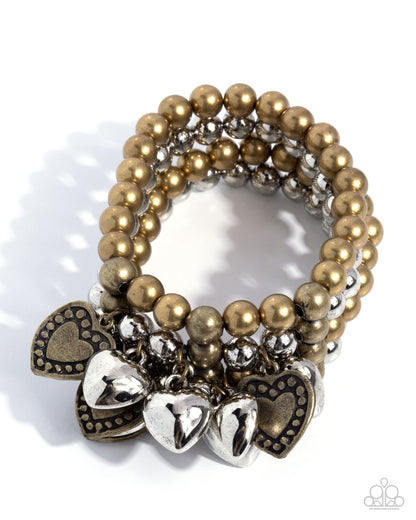 Gold and silver beaded bracelet with heart charms on a white background