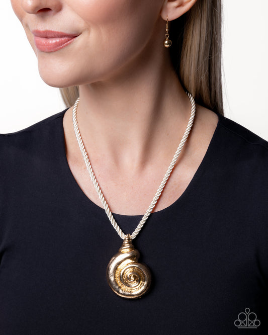 Gold spiral pendant necklace on a person wearing a black top against a white background