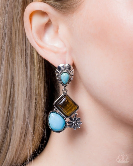 Close-up of an ear wearing a silver earring with turquoise and brown stones.