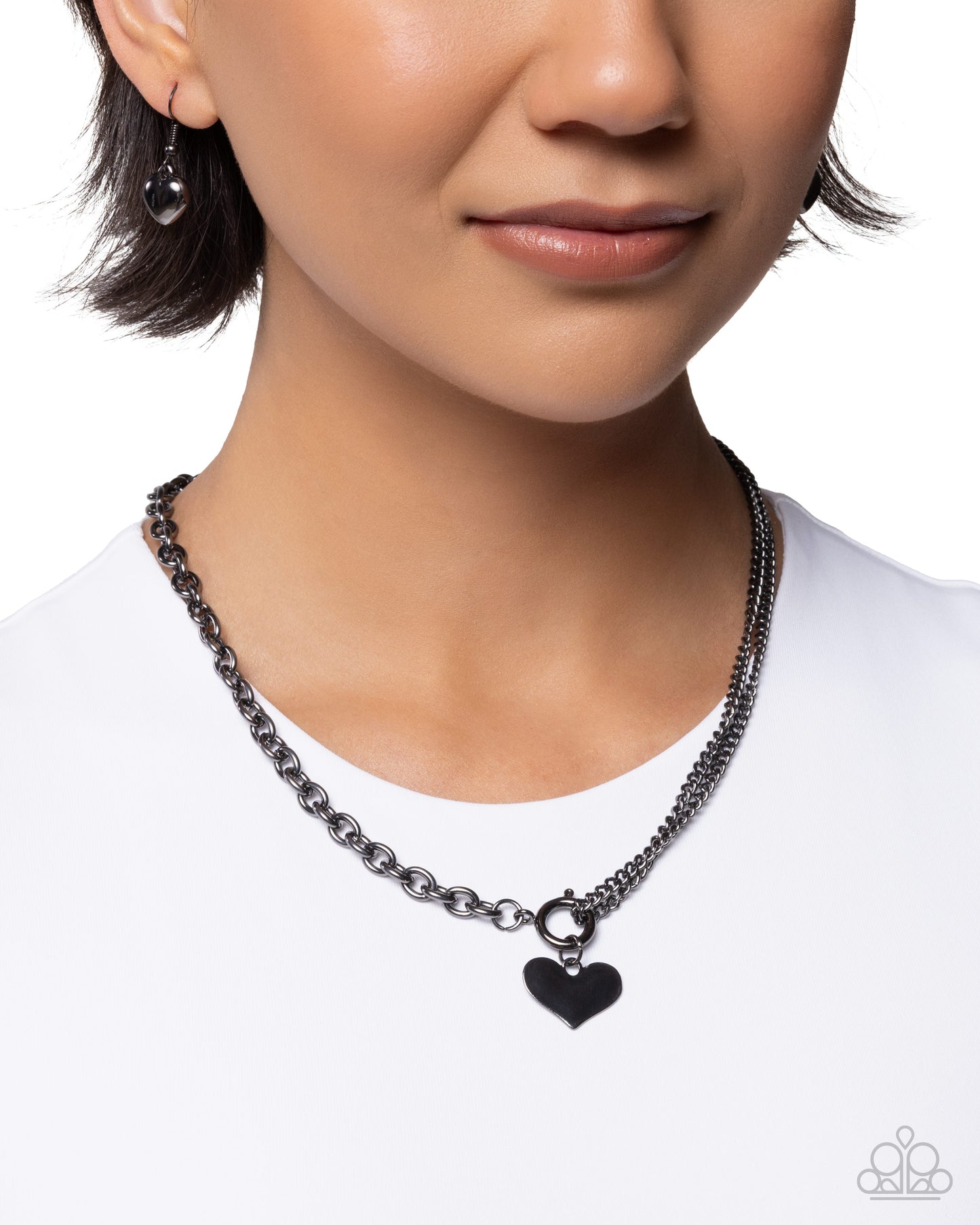 Person wearing a black chain necklace with a heart pendant on a white background