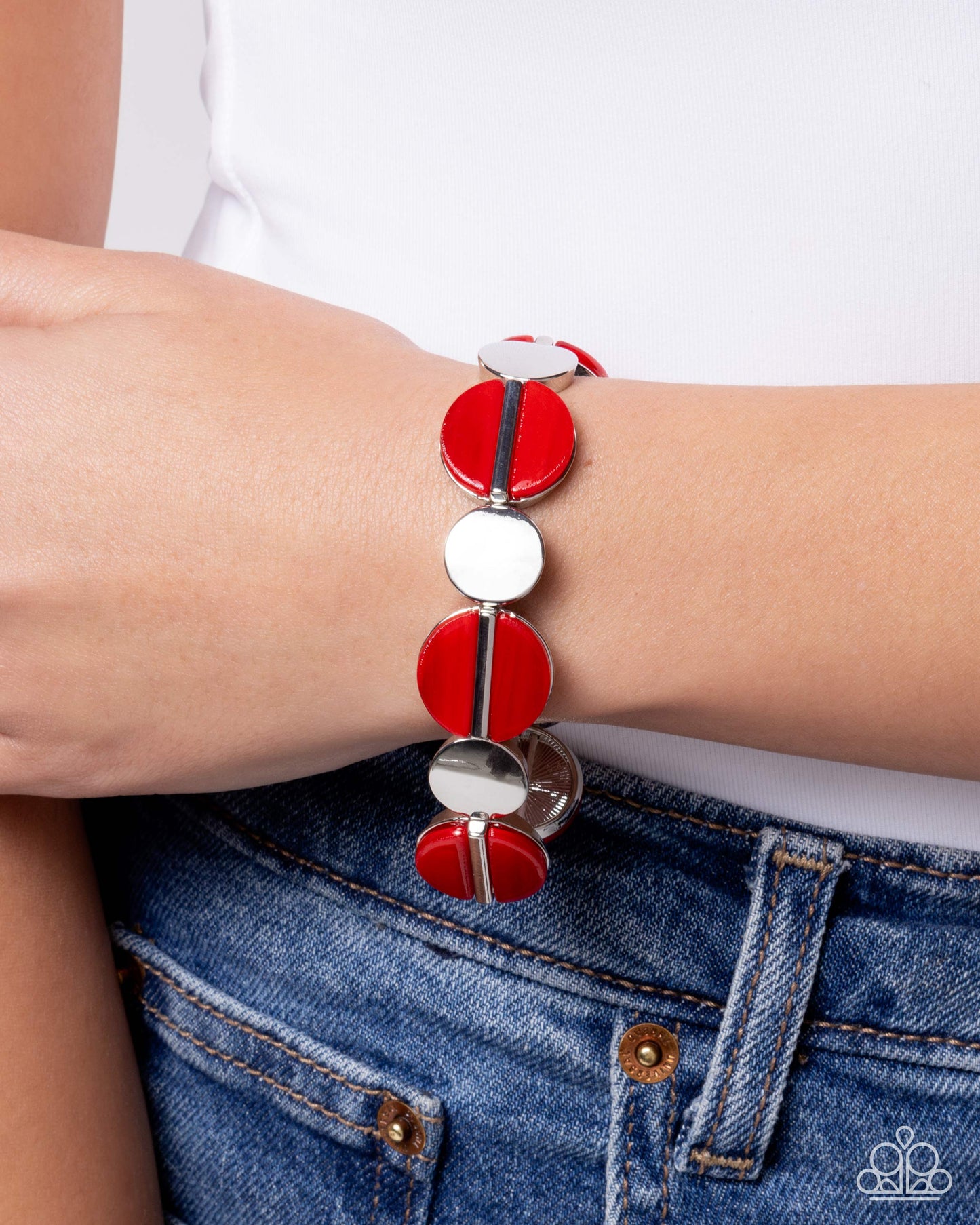 Bracelet with red and silver circular beads on a wrist, against a white background.