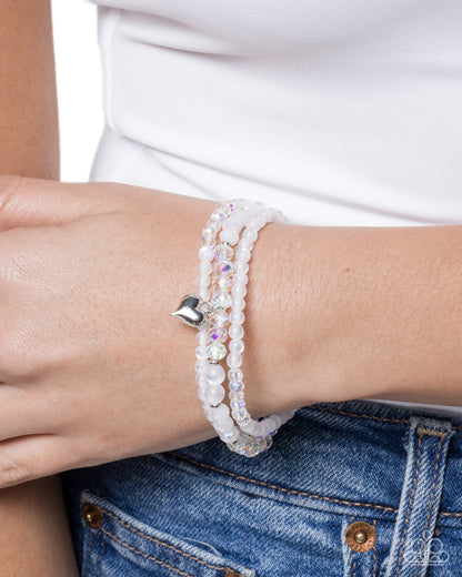 Close-up of a wrist wearing two beaded bracelets with a white shirt and blue jeans.