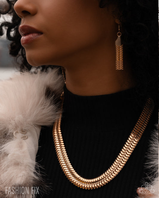 Close-up of a person wearing a gold necklace and tassel earring with a blurred background.