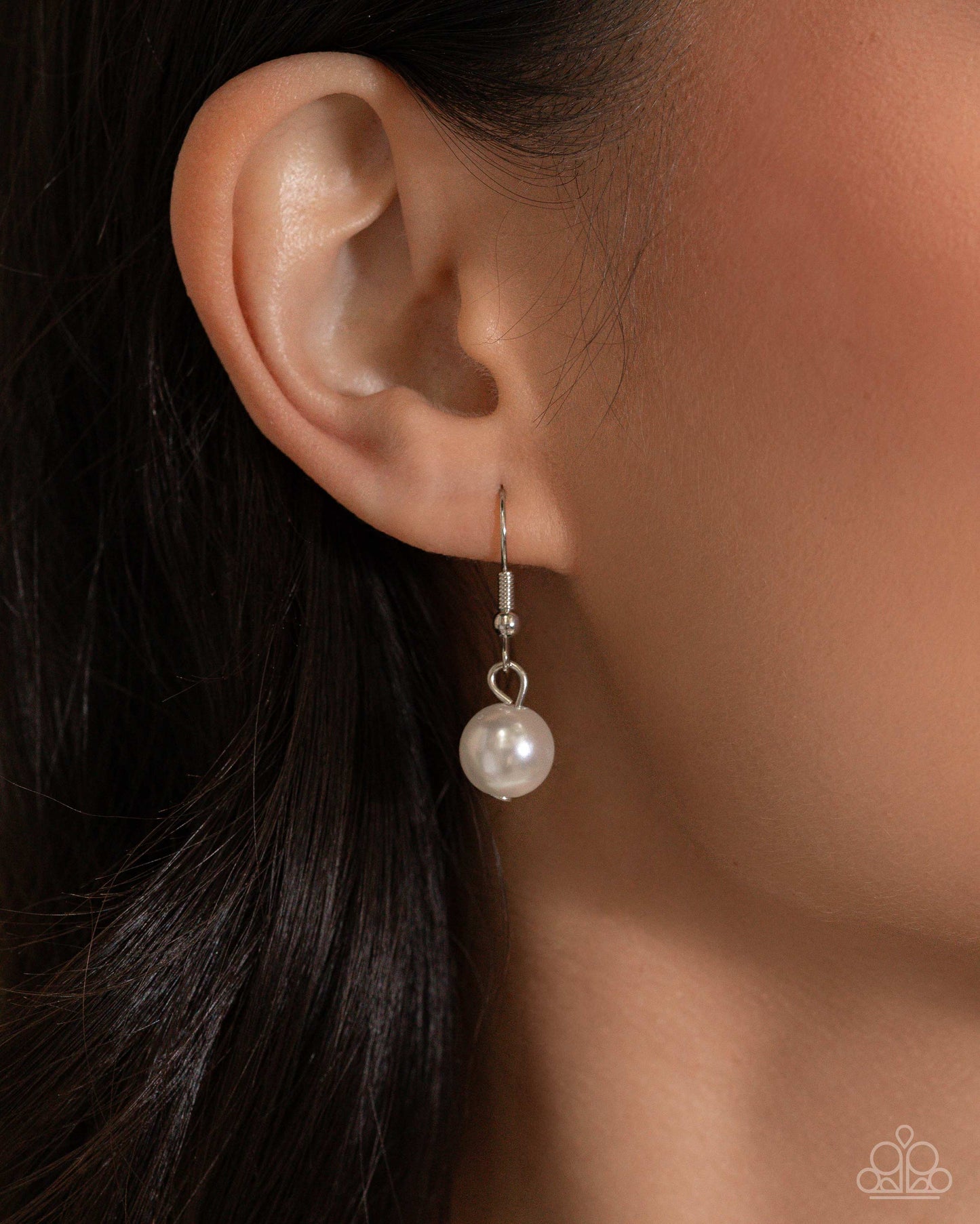 Pearl earring worn on an ear with a blurred background