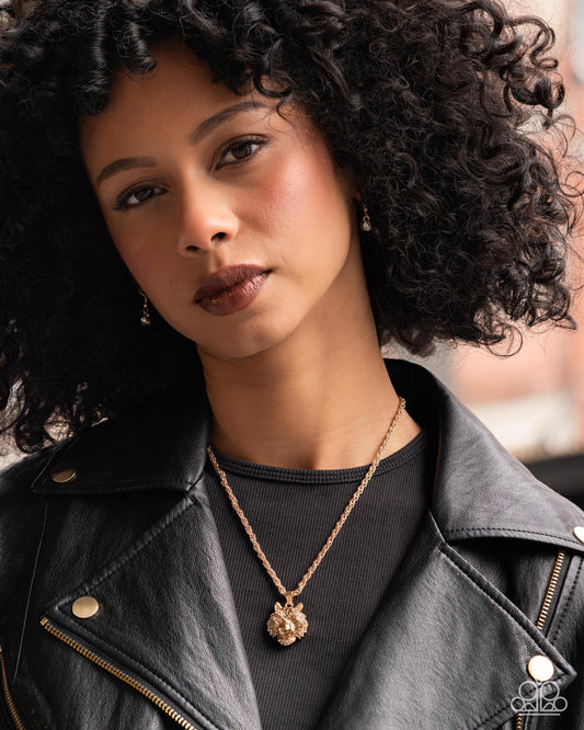 Woman wearing a black leather jacket and gold necklace with a pendant.