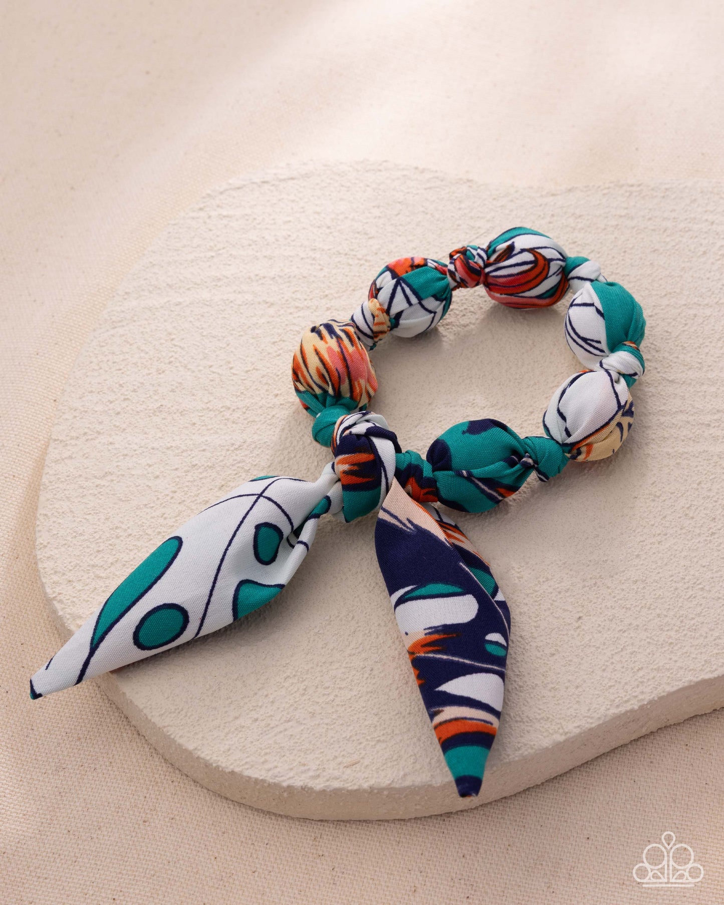 Colorful beaded hair tie on a beige stone surface