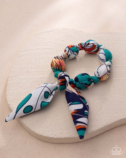 Colorful beaded hair tie on a beige stone surface