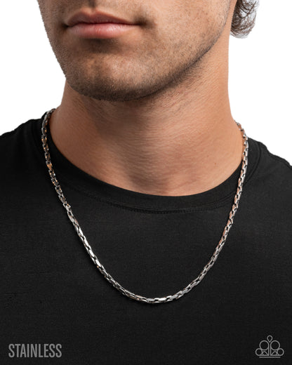 Silver chain necklace worn by a person on a black background
