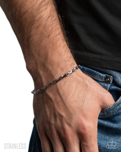 Close-up of a hand wearing a silver chain bracelet on a white background