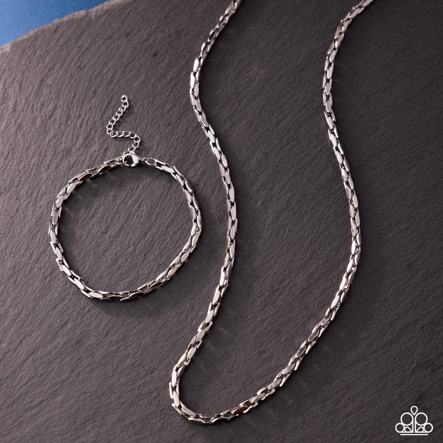 Silver chain necklace on a dark stone surface