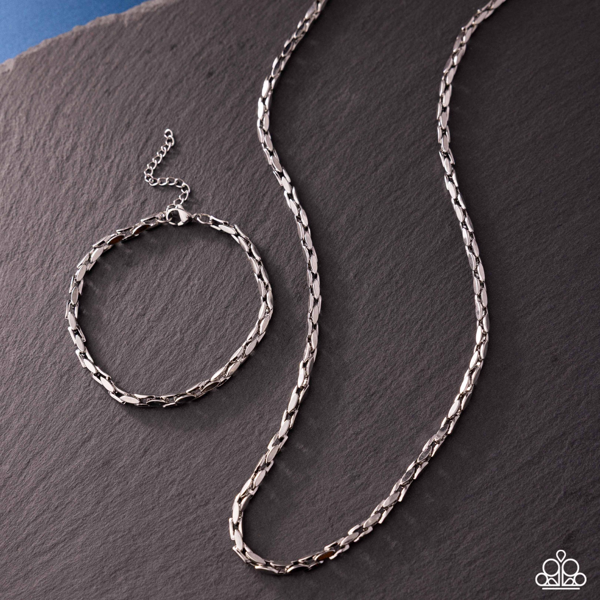 Silver chain necklace on a dark stone surface