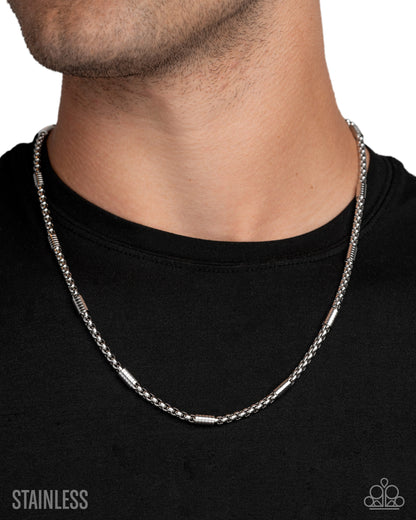 Silver chain necklace worn by a person on a black background