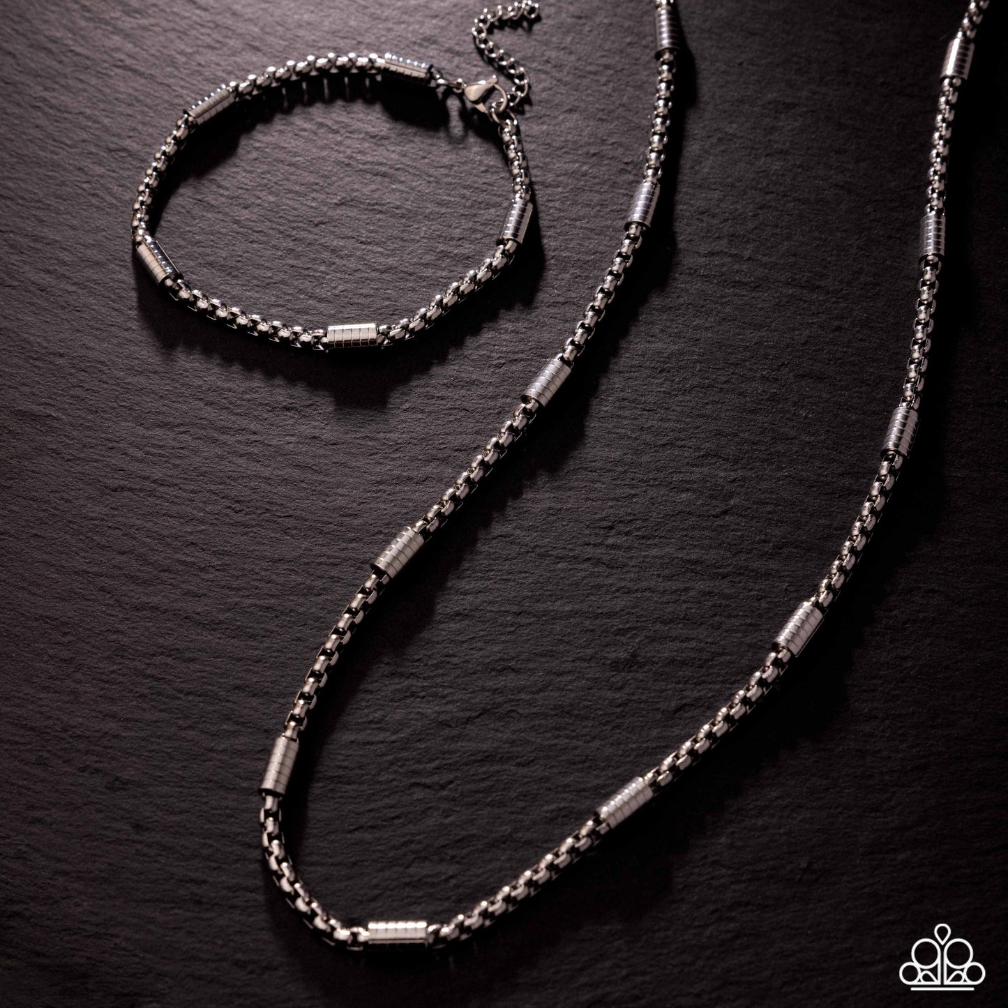 Silver bracelet and necklace set on a dark textured surface