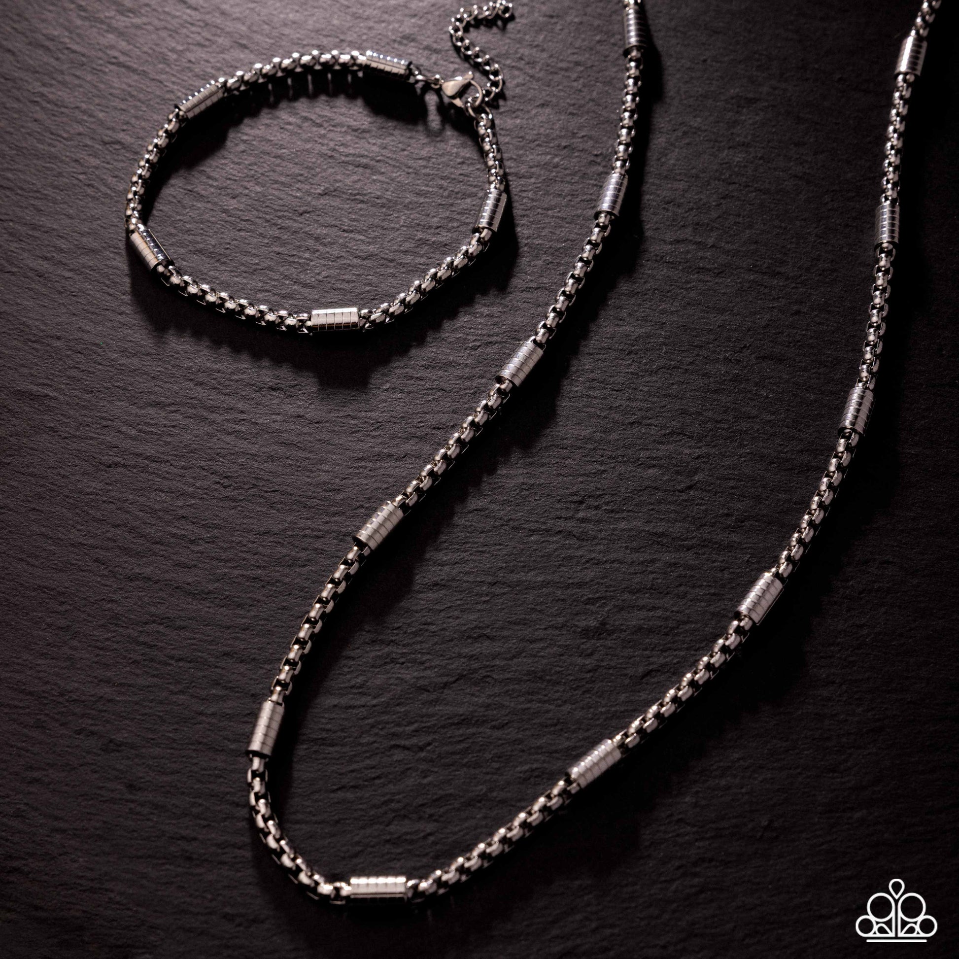 Silver bracelet and necklace set on a dark textured surface