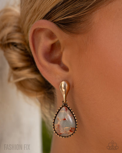 Teardrop-shaped earring worn by a person with blonde hair, against a neutral background.