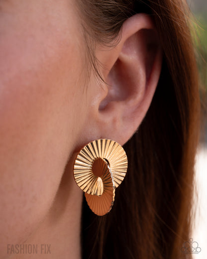Gold earrings worn by a person with brown hair.