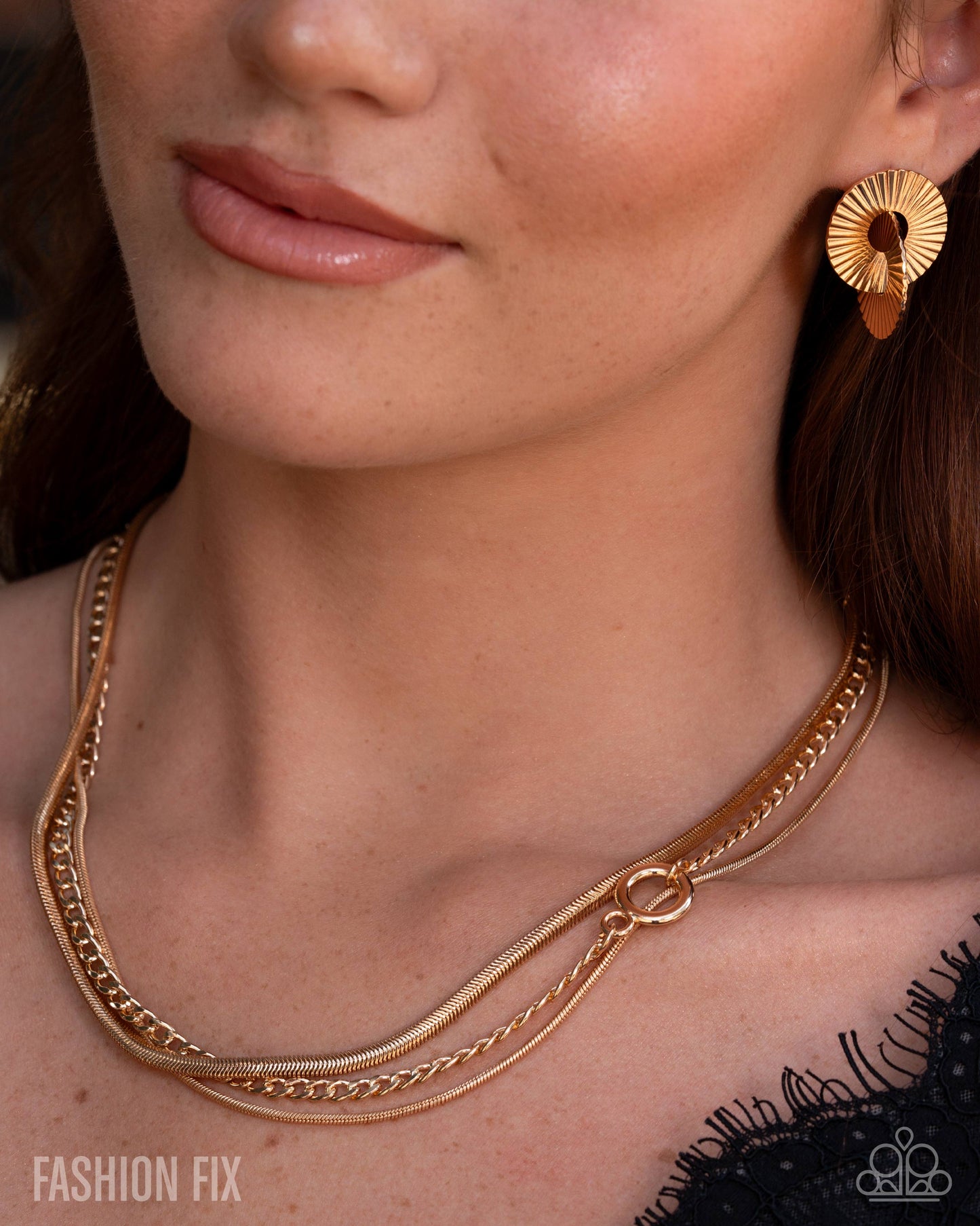 Close-up of a woman wearing gold jewelry including a necklace and earrings.