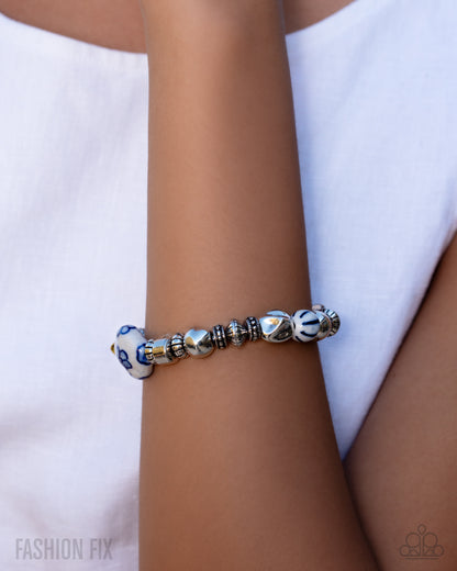 Bracelet with blue and white beads on a wrist against a white background
