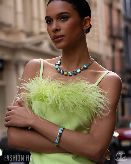 Woman wearing a bright green dress with feather details and a colorful necklace in an urban setting.