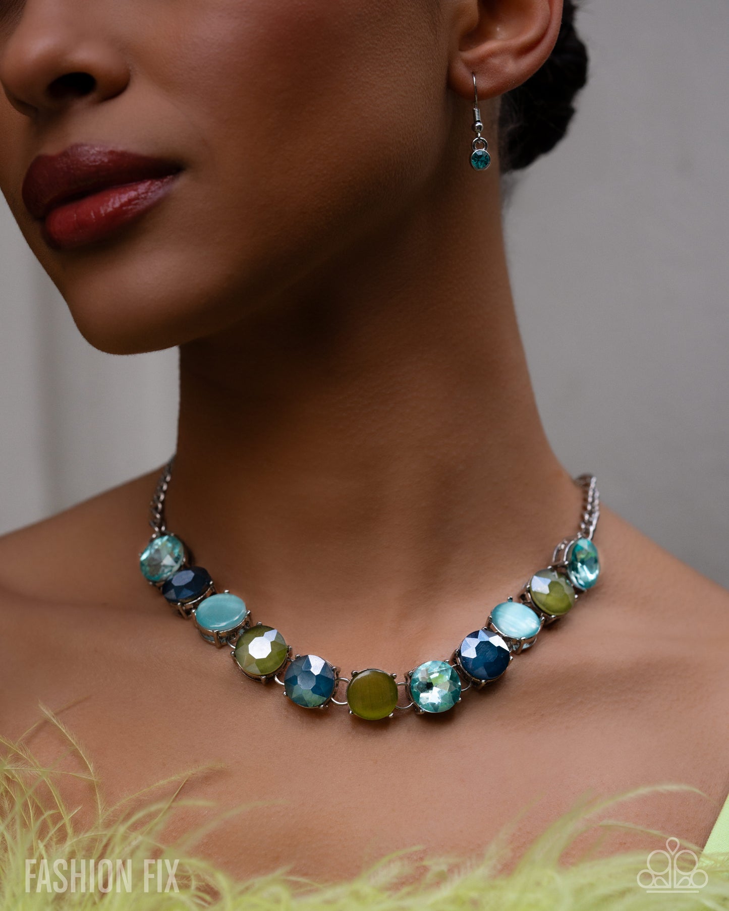 Necklace with blue and green gemstones worn by a model against a neutral background