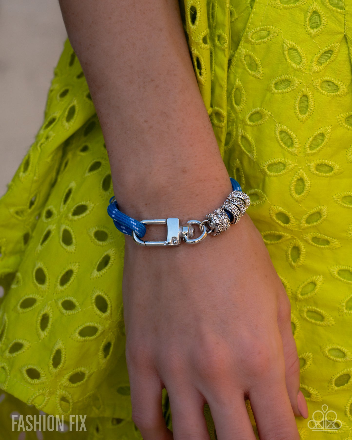 Bracelet with blue and silver design on wrist against a yellow fabric background